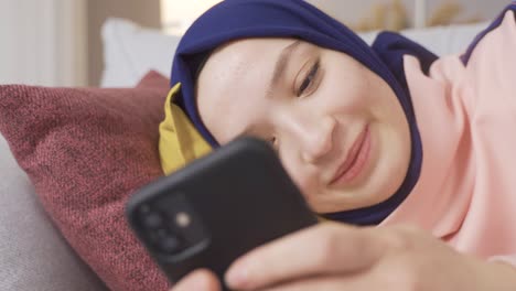 Zufriedenes-Muslimisches-Mädchen-Mit-Hijab-Benutzt-Zu-Hause-Das-Smartphone.